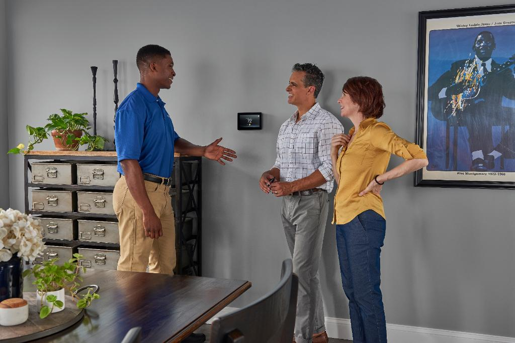 Carrier technician with homeowners at thermostat